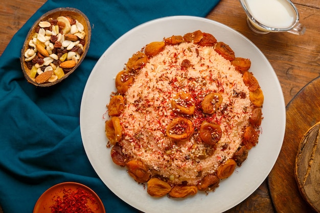 Couscous masfouf with dried fruits and nuts on a wooden table next to almond milk and nuts