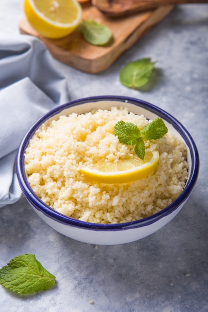 Couscous met hierboven munt en citroen in plaat op donkere rustieke lijst van