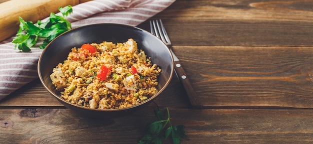 Couscous met kalkoen, tomaten, champignonpaddestoelen en avocado op houten achtergrond. Traditioneel gerecht in het Midden-Oosten en het Middellandse Zeegebied. Lange brede banner