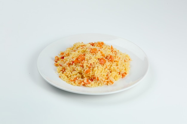 Couscous met wortelen in witte plaat close-up. coucous geïsoleerd op witte achtergrond