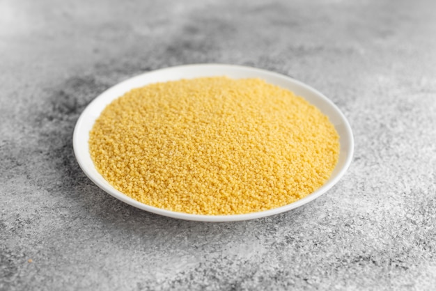 Couscous in a white saucer on a gray concrete background