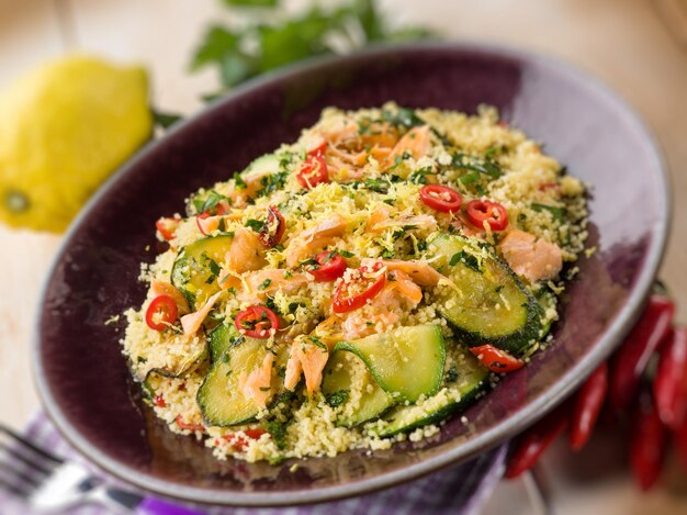 Photo couscous with fresh salmon zucchinis and hot chili pepperselective focus