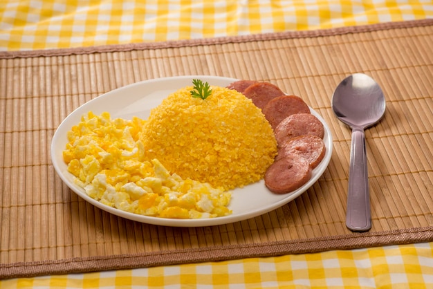 Couscous with scrambled eggs and pepperoni sausage on bamboo mat and yellow fabric ( cuzcuz )