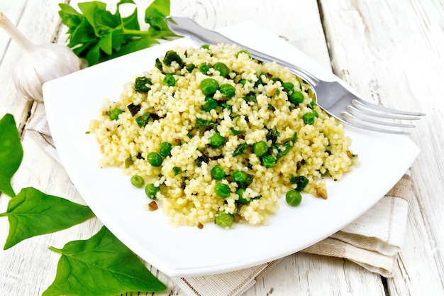 Couscous with spinach in plate on light board