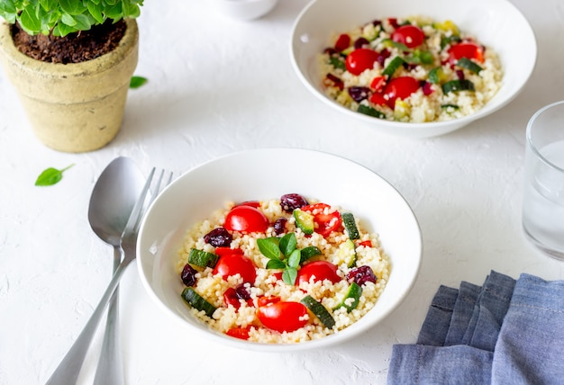 Couscoussalade met tomaten, paprika's, courgettes en veenbessen. Vegetarisch eten. Eetpatroon. Gezond eten.