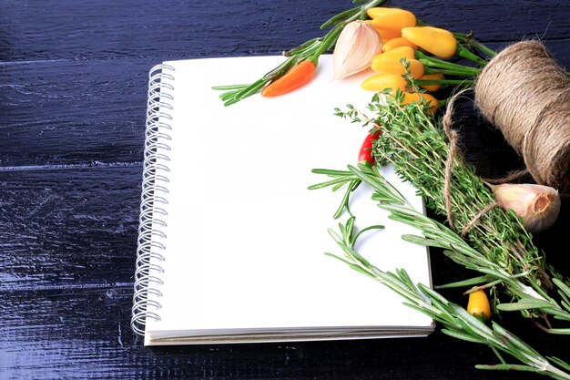 写真 ニンニクタイムコショウの黒の木製テーブルスパイスレシピの料理本ノートをカバーします。