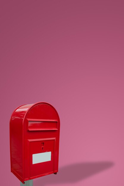 Photo cover page with big fancy red metal postbox with white empty note space for address isolated at pink gradient background with copy space concept of communication and post service