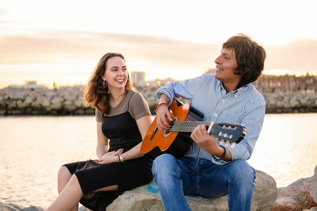 Coverband couple of musicians play acoustic guitar and sing near the beach. Sea on background