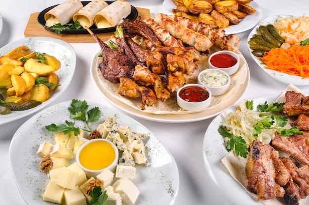 A covered table with many different dinner dishes. Lots of food on a white isolated background