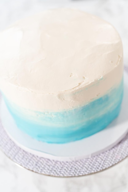 Covering 3 layer vanilla cake with buttercream frosting to create mermaid-themed 3 layer vanilla cake.