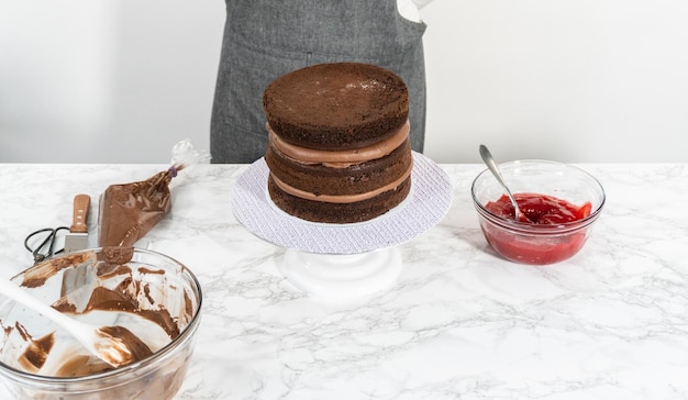 Covering chocolate cake with a crumb layer of chocolate buttercream frosting.