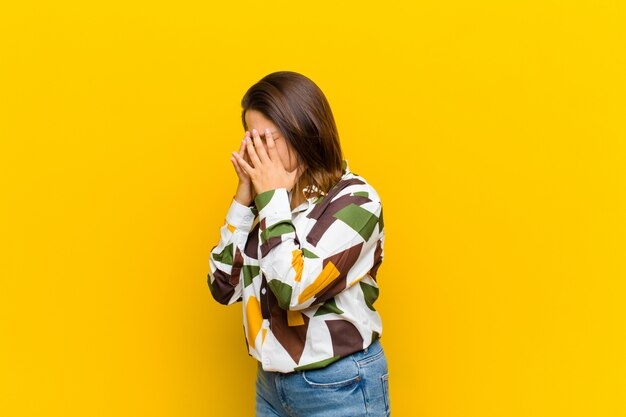 Coprendosi gli occhi con le mani con uno sguardo triste e frustrato di disperazione, pianto, vista laterale