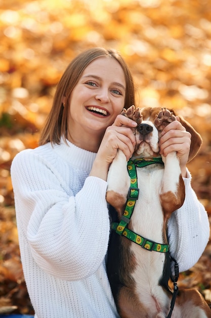 Photo covering eyes with paws woman is with her cute dog in the autumn forest
