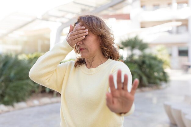 Covering face with hand and putting other hand up front to stop camera refusing photos or pictures