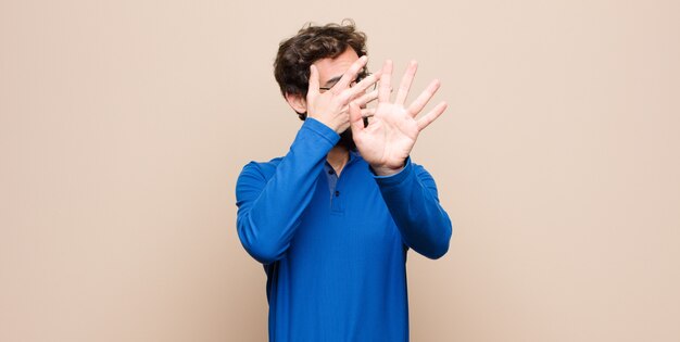 covering face with hand and putting other hand up front to stop camera, refusing photos or pictures