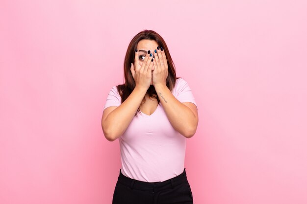 covering face with hands, peeking between fingers with surprised expression and looking to the side