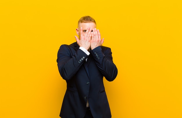 covering face with hands, peeking between fingers with surprised expression and looking to the side