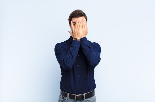 covering face with hands, peeking between fingers with surprised expression and looking to the side