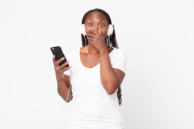 Covering mouth with hands with a shocked with headphones and a smart phone