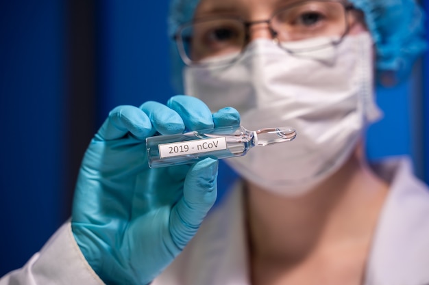 Covid-19. 2019 nieuw coronavirus (2019-ncov) concept. een ampul met een vaccin in de hand van de dokter. vaccinatie tegen coronavirus helpt de immuniteit te versterken.