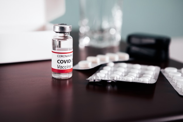 COVID-19 Ampoules with vaccine and pills on a table. Healthcare And Medical concept.