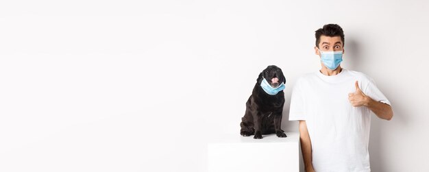 Photo covid-19 animals and quarantine concept image of funny young man and small dog in medical masks           person