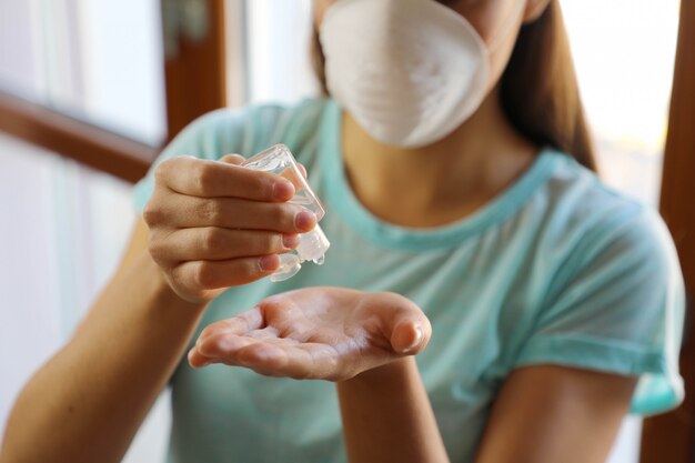 COVID-19 Close up woman hands using wash hand sanitizer gel dispenser, against Novel coronavirus (2019-nCoV) at home.