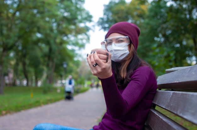 COVID-19-concept. Vrouw met medisch masker en veiligheidsbril die handen wassen met ontsmettingsmiddel voor alcoholgel. Bescherming en preventie tegen het coronavirus.