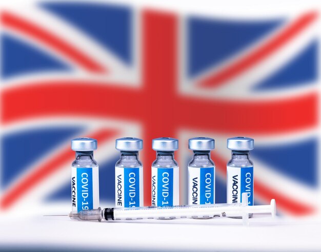 Covid 19 corona virus vaccine bottles and syringe with a UNITED KINGDOM  National flag background