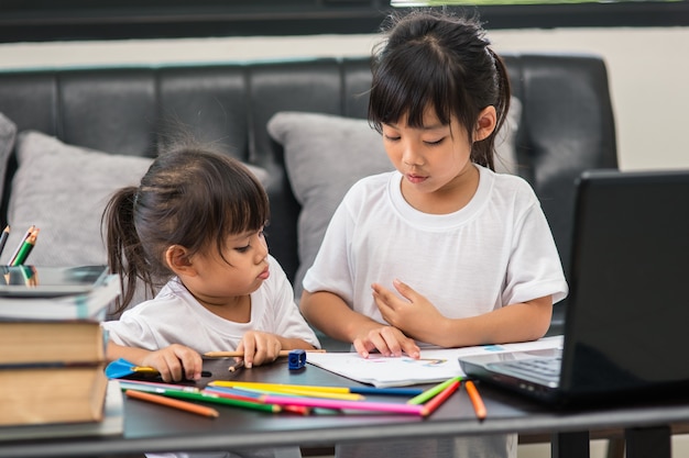 Covid-19 Coronavirus en leren vanuit huis, thuisschoolconcept. Kleine kinderen studeren online leren vanuit huis met laptop.