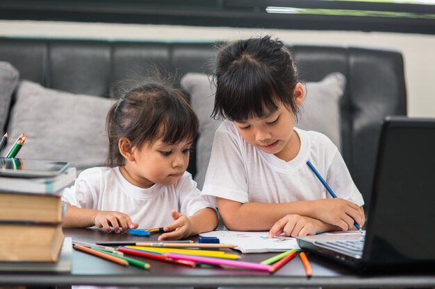 Covid-19 Coronavirus en leren vanuit huis, thuisschoolconcept. Kleine kinderen studeren online leren vanuit huis met laptop.