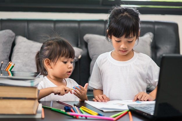 Covid-19 Коронавирус и обучение из дома, концепция домашнего школьника. Маленькие дети изучают онлайн-обучение дома с ноутбуком.