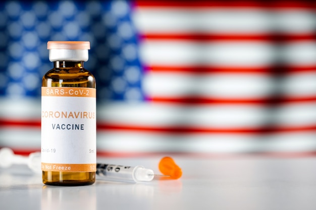 Photo covid 19 coronavirus vaccine with a dose in a syringe against the background of the usa flag. the concept of vaccination and immunization against coronavirus in united states.