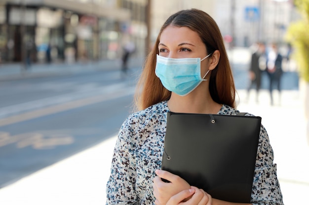 Covid-19 global economic crisis maschera medica per ragazza disoccupata in cerca di lavoro camminando per una strada cittadina fornire curriculum vitae