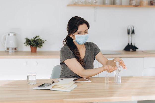 Covid-19 jonge vrouw die thuis een handdesinfecterende geldispenser gebruikt, tegen nieuw coronavirus (2019-ncov) thuis. huisisolatie, auto quarantine, antiseptic, hygiene en healthcare concept.