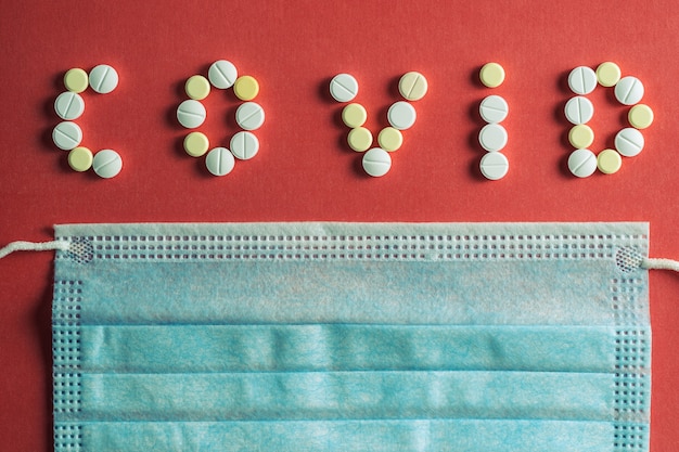 Lettere covid 19 fatte di pillole mediche bianche su una superficie rossa brillante
