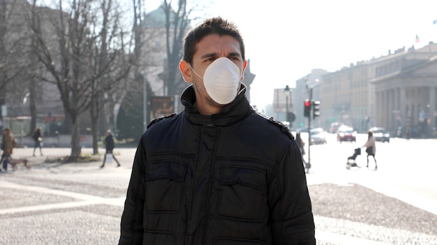 COVID-19 Man in city street wearing face mask protective for spreading of disease virus: Coronavirus Disease 2019.