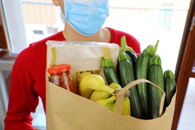 Covid-19 pandemic coronavirus man with mask delivering online grocery order