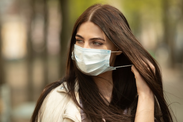 COVID-19 Pandemic Coronavirus Woman on city street wearing face mask protective for spreading of disease virus. Girl with protective mask on face against Coronavirus Disease 2019.