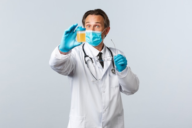 Covid-19、ウイルス、医療従事者、予防接種の概念を防ぎます。興奮した研究室の科学者、診療所の医師は、患者の尿のテストサンプルを示す医療用マスクと手袋を着用します