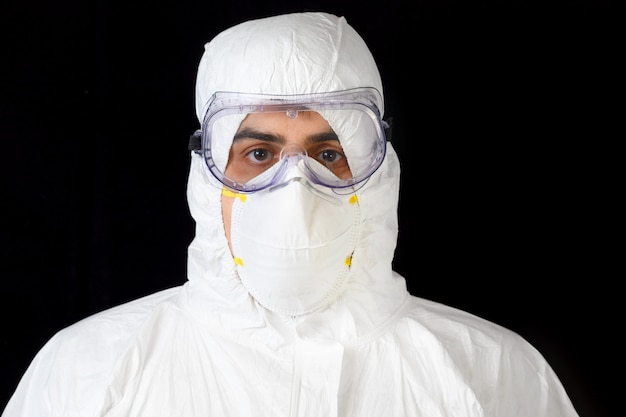 Covid-19 protective equipment. Portrait of Doctor or male nurse Wearing Personal Protective Equipment on black isolated