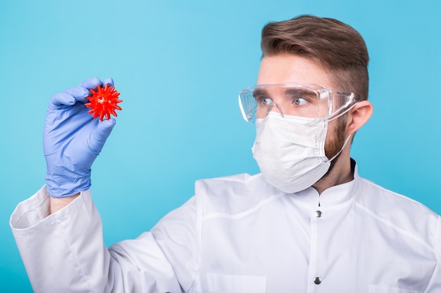 Covid-19, 백신 개발 및 의학 개념-독감 마스크 및 코로나 바이러스 모델을 들고 보호 장갑 남자 과학자.