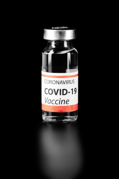 黒の背景に分離されたCOVID-19ワクチン。ヘルスケアと医療の概念。