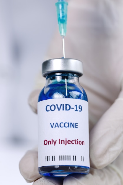 COVID-19 vaccine in researcher hands, unrecognizable female doctor holds syringe and bottle with vaccine for coronavirus cure. 