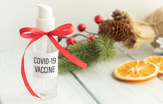 빨간 리본, 새해 개념 및 COVID 예방 접종으로 항아리에 Covid-19 백신 텍스트