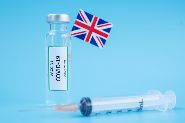 Covid-19 vaccine vial, injection needle syringe and united kingdom flag