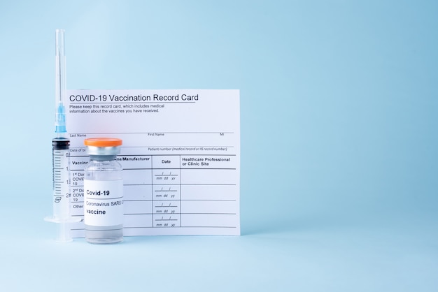 Covid-19 vaccine vial, vaccination record card, syringe. Coronavirus vaccination concept.