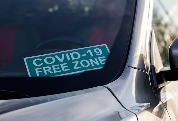 Covid-19 vrije zone. Een kartonnen bord op de voorruit in de auto.