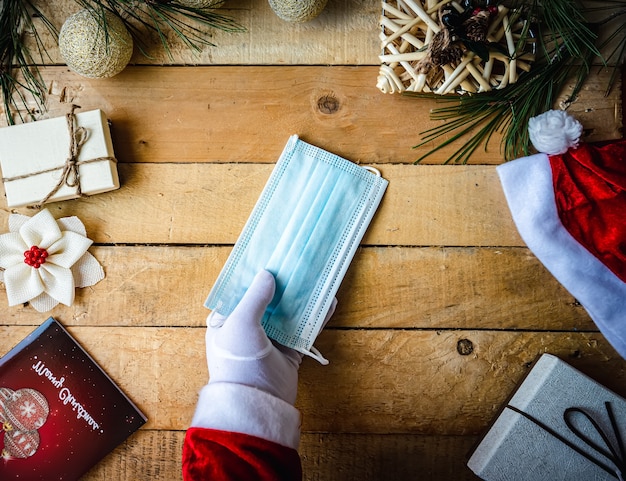 Covid Christmas shot van santa dient witte handschoenen in met een sanitair masker op kerstversiering