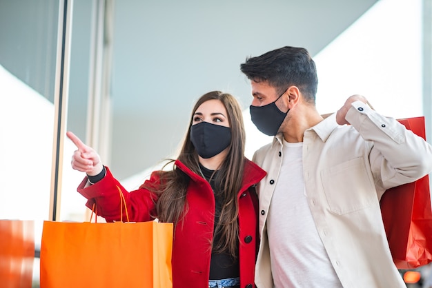 Shopping di covid e coronavirus, giovane coppia che cammina in una città mentre trasporta borse della spesa